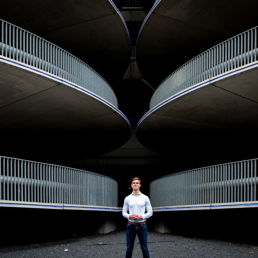 An environmental portrait of Daan for Grip on Finance. The image is perfectly symmetrical, with the garage ramps and exits creating dynamic lines that all point towards Daan, placing him at the center of attention.
