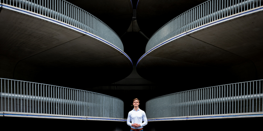 Een omgevingsportret van Daan voor Grip op Finance. Het beeld is perfect symetrisch. De opritten en uitritten van de garage geven het beeld spannende lijnen. Ze wijzen naar Daan die daardoor in het middelpunt komt te staan.