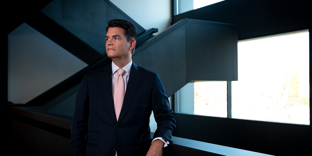 Een omgevingsportret van Alexander Doorman voor Freshfields in het kantoor met een moderne trap op de achtergrond.