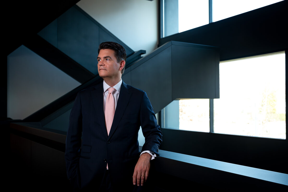 Een omgevingsportret van Alexander Doorman voor Freshfields in het kantoor met een moderne trap op de achtergrond.