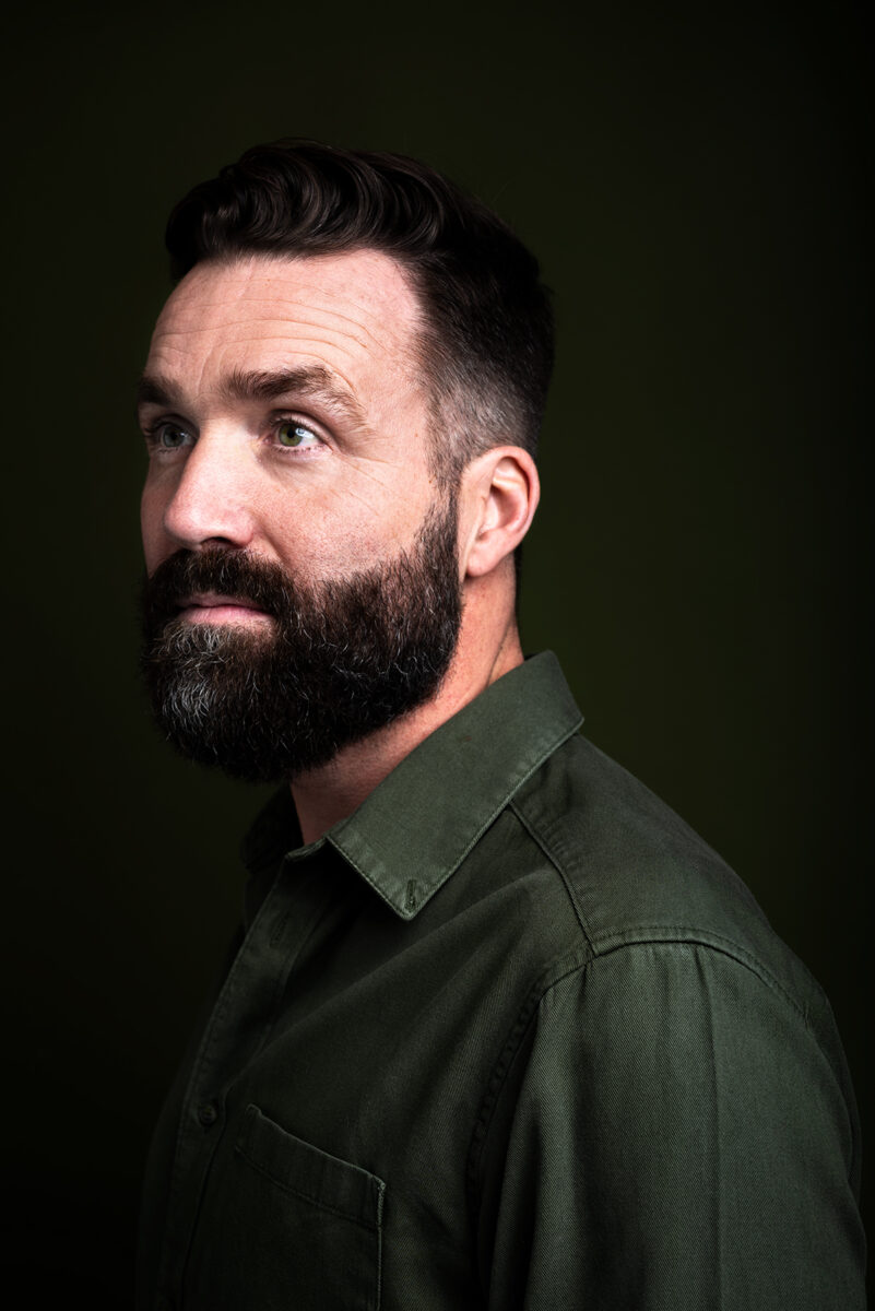 Een portret van Hans Bouwens met groene achtergrond en groene kleding gemaakt in de studio.