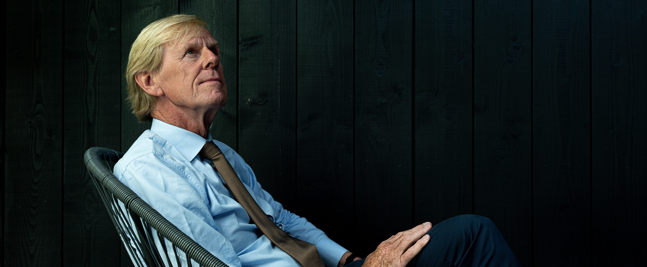 An environmental portrait of Henk Rottinghuis sitting on a Acapulco chair. The light is natural and coming from a glass ceiling.