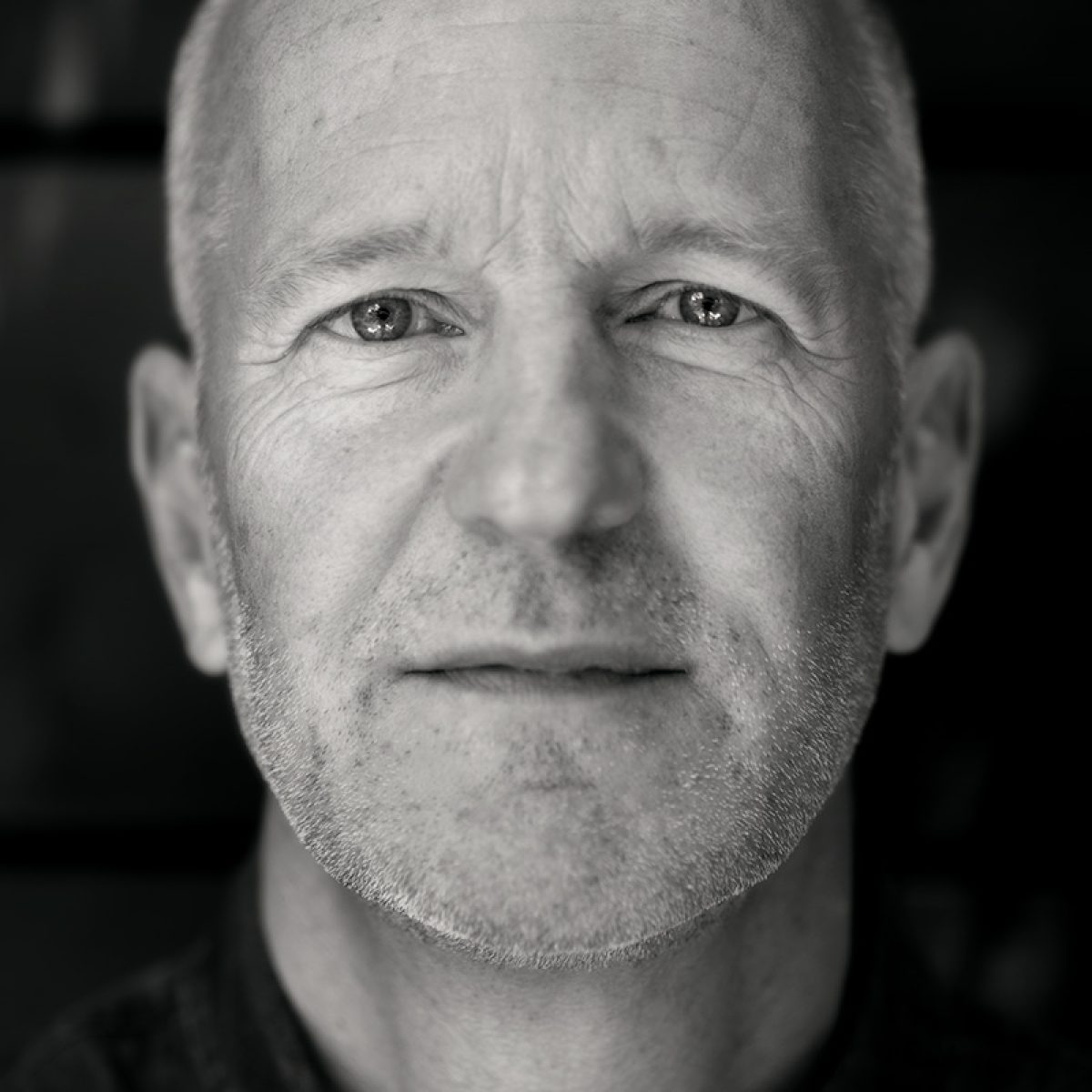 Close-up portret van Norbert van der Hoeven met rustige blik tegen donkere achtergrond